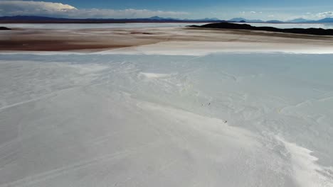 very tiny people walk on vast salt flat at uyuni, bolivia, aerial view