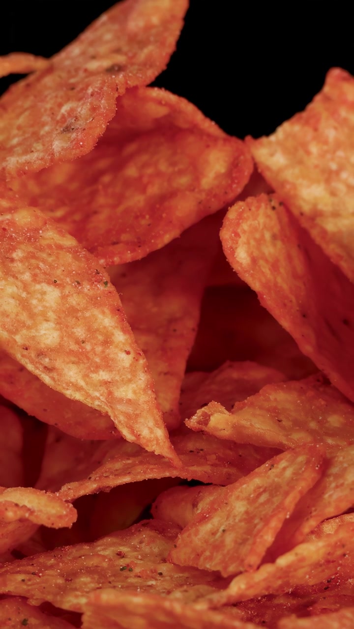 Tortilla chips dorate che cadono al rallentatore, illuminazione drammatica, primissimo piano, sfondo nero