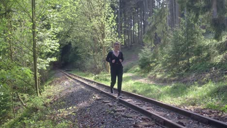 Front-view-of-a-tourist-girl-walking-on-an-unused-railway-track