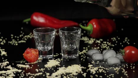 Pour-vodka-into-shot-glasses-placed-on-a-black-surface