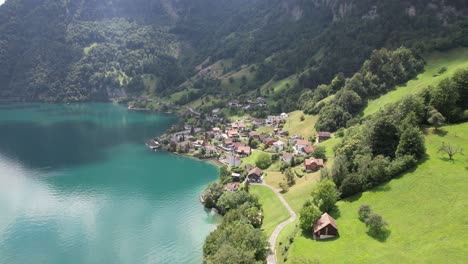 Lago-Azul-Y-Pequeño-Pueblo-Suizo-Drone-Vista-Montañas-Y-Naturaleza