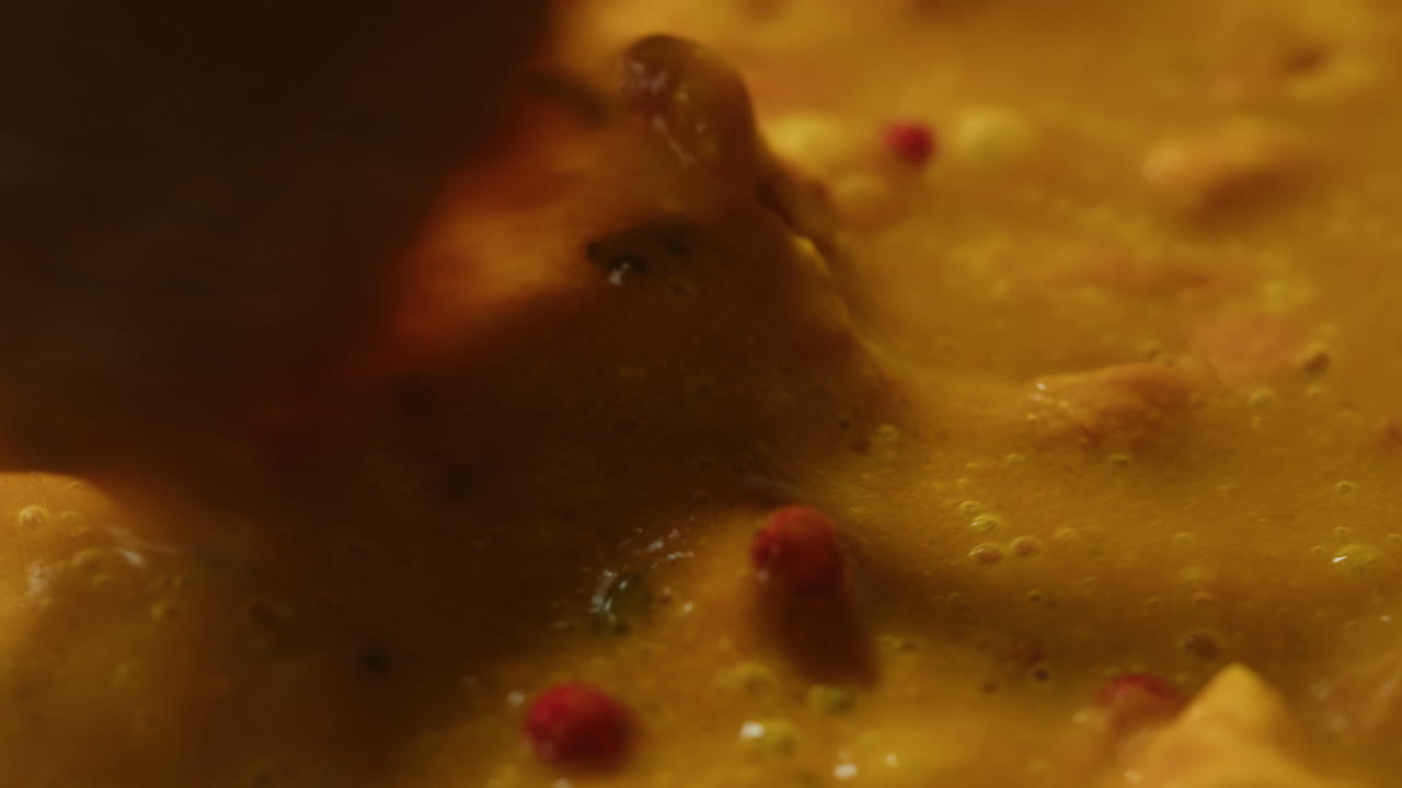 Yellow boiling sauce on pan close-up. Asian cuisine concept. Curry is a dish with a sauce seasoned with spices. Curries may contain fish, meat, poultry, or shellfish, either alone or in combination with vegetables. Others are vegetarian.