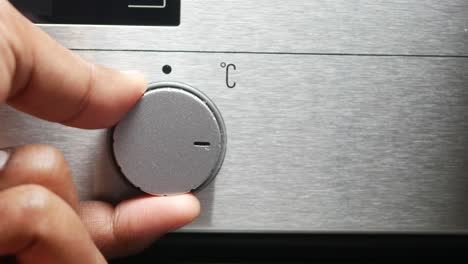 closeup of a hand turning an oven knob