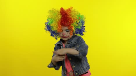 una niña payasa con una peluca colorida haciendo caras tontas. divirtiéndose, sonriendo, bailando. halloween