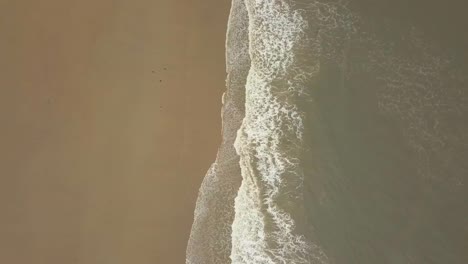 Aerial-birds-eye-view-drone-footage-of-waves-crashing-onto-the-beach,-Seaburn-Beach,-Sunderland