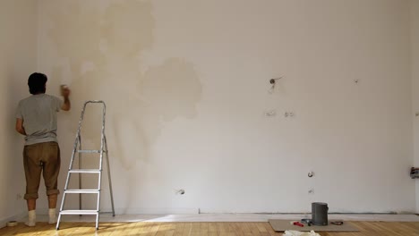 a man painting wall using a limewash grey paint