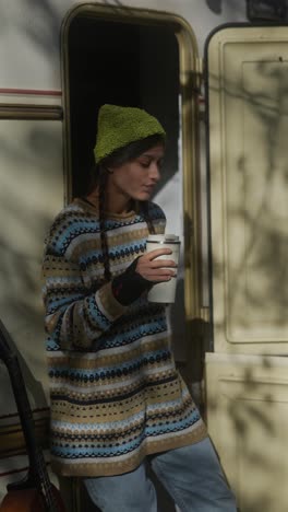 woman enjoying coffee outdoors near a camper van