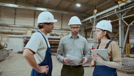 ingeniero con documentos e instruyendo a dos técnicos de la fábrica