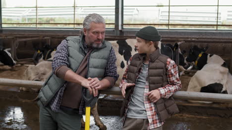 farmer and boy talking in a dairy farm barn