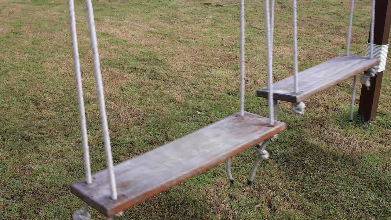 아무도 앉아 있지 않은 상태에서 앞뒤로 흔들리는 4k 두 개의 나무 로프 스윙