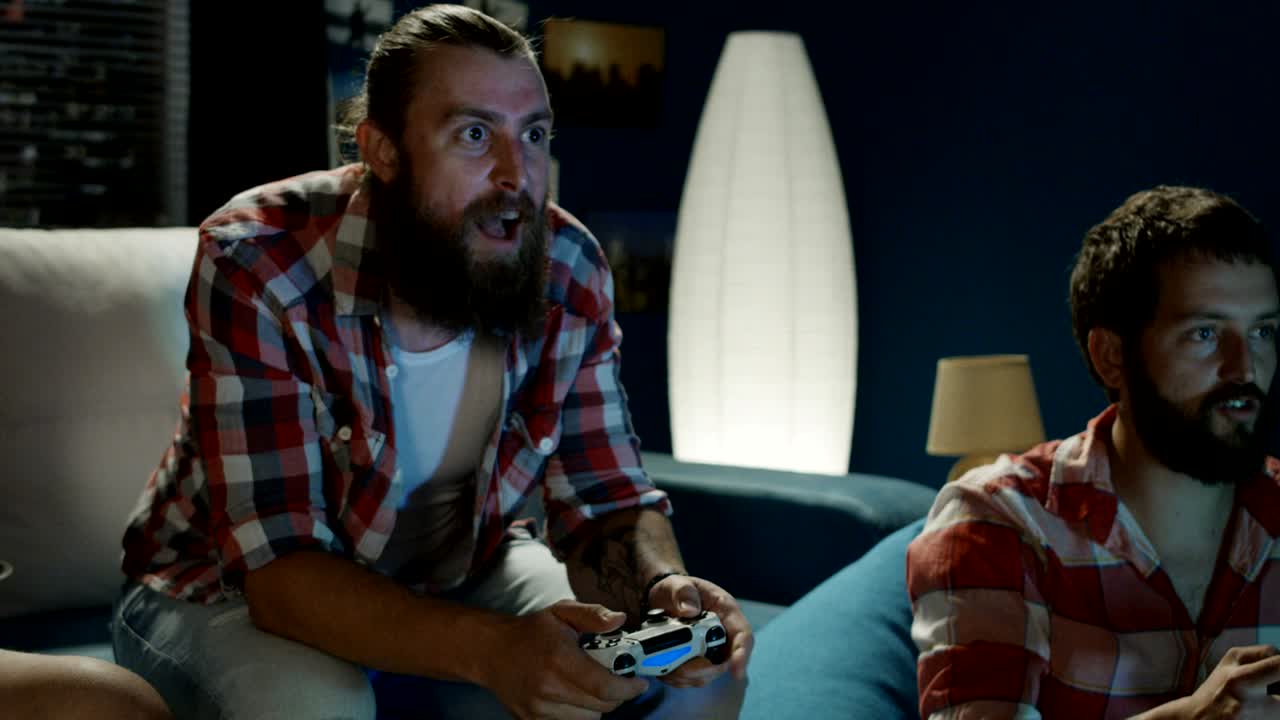 hombres jugando con gamepads en casa