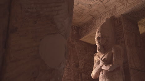 acending shot inside abu simbel of a big osiris statue