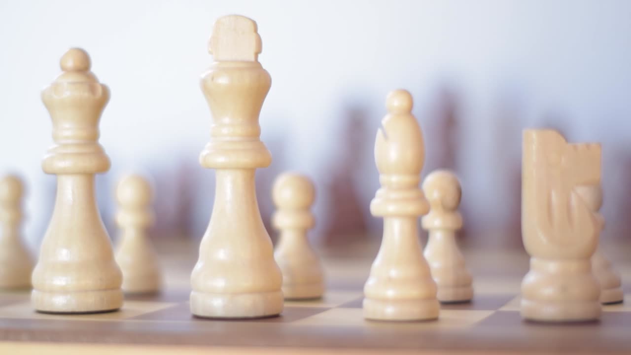Close up of focusiung from the white to the black chess figures on a wooden chessboard.