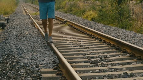 detalhe dos pés de um homem se equilibrando nos trilhos do trem em uma estação possivelmente abandonada, como fazia quando criança