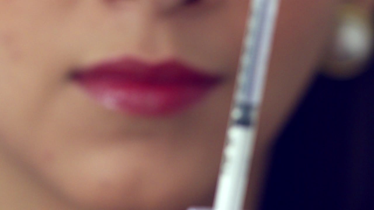 llenado de una jeringa de un vial - cierre con enfoque de rack a la cara del médico