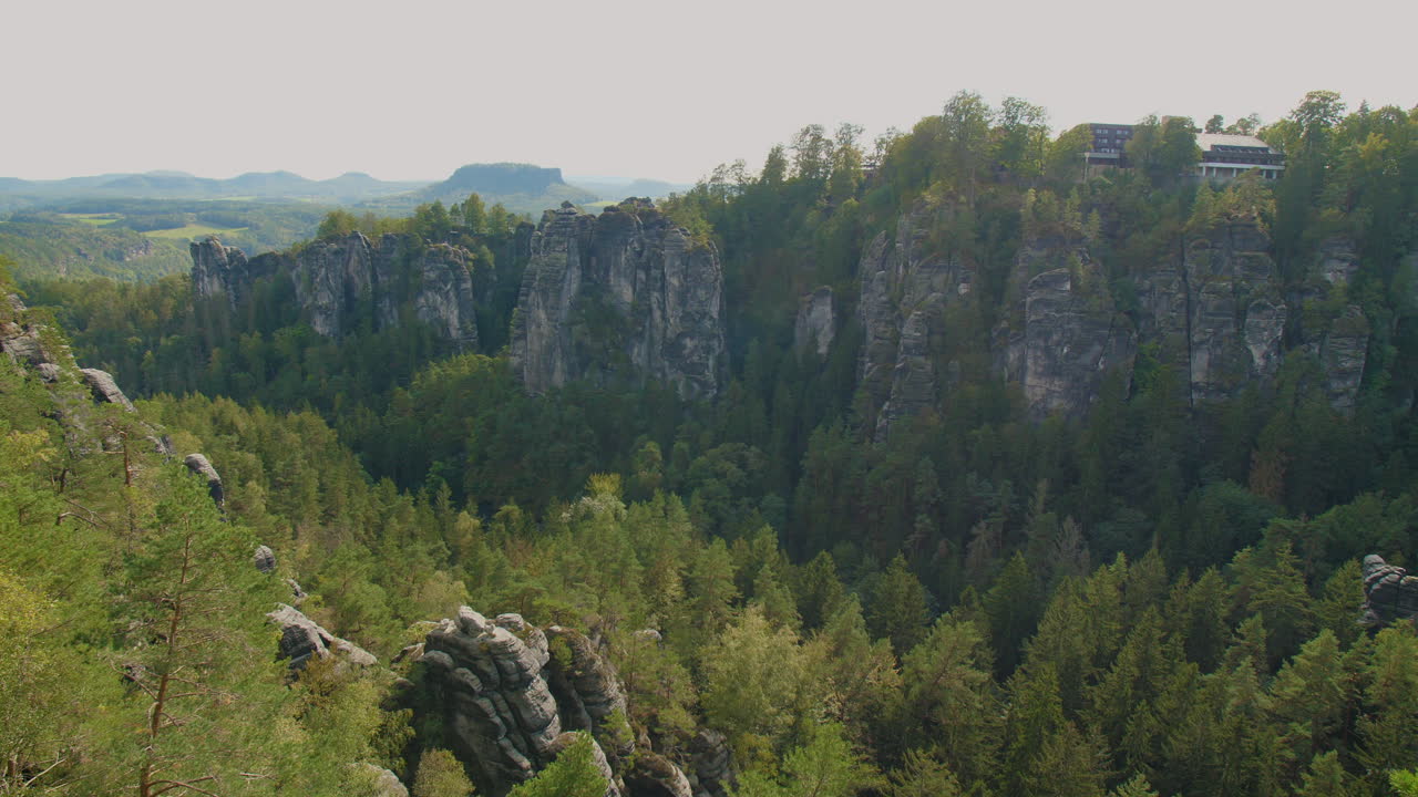 Elbsandsteingebirge Sachsen Elbe sandstone formations rising above dense green forests Mountains, under a blue sky with scattered clouds, showcasing the region’s natural beauty rugged Terrain
