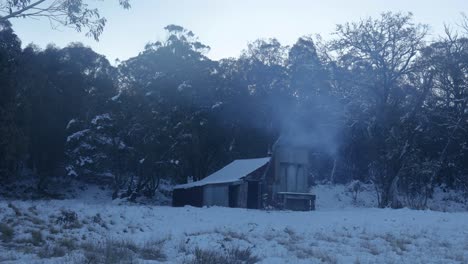 rustic hut in a snowy winter forest with smoke from chimney