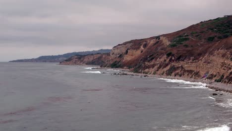 vista aérea de pájaro de arriba hacia abajo de las olas rompiendo en una playa rocosa del sur de california