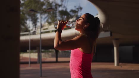 mujer caucásica bebiendo agua debajo de un puente
