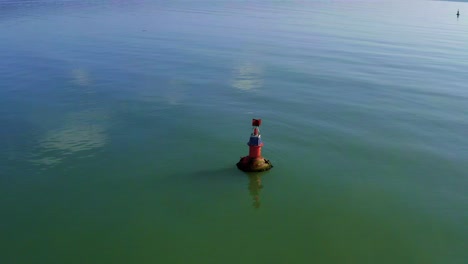 aerial orbit flying over orange navigational aid marker on calm sea water