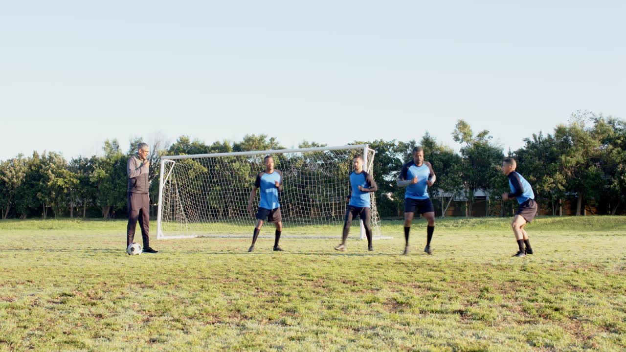 Playing soccer, coach instructing young players on field near goalpost