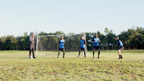 playing soccer, coach instructing young players on field near goalpost