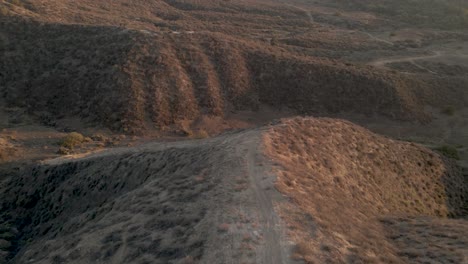 Aerial-view-of-trails-on-top-of-a-mountain-at-sunset