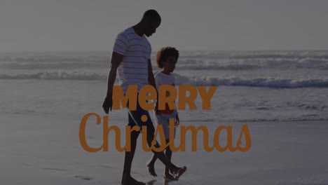 Animation-of-merry-christmas-text-over-african-american-man-and-his-son-at-beach