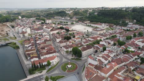 Tomar,-Portugal,-Mostrando-Edificios-Con-Techos-Rojos,-Exuberante-Vegetación-Y-Río,-Vista-Aérea