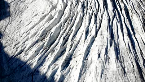 sobrevuelo aéreo sobre las grietas del glaciar morteratsch en engadin, suiza al amanecer con una vista aérea del hielo