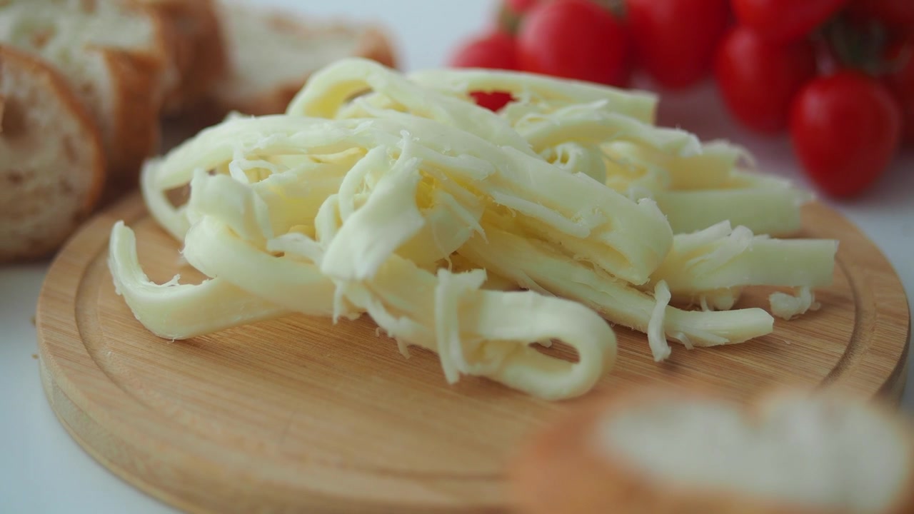 Mozzarella fresca sfilacciata su un tagliere di legno
