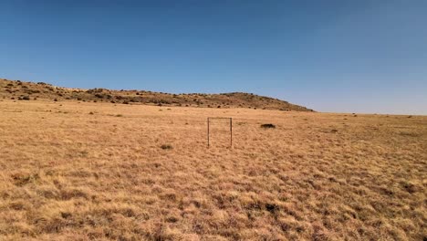 Solitary-rusty-metal-signboard-in-an-abandoned-farmland-field,-a-relic-of-bygone-times,-weathered-and-forgotten