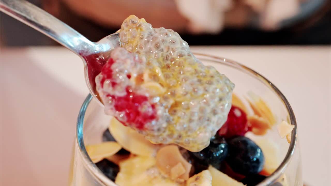 Close up of a woman eating chia pudding with fruit at a cafe