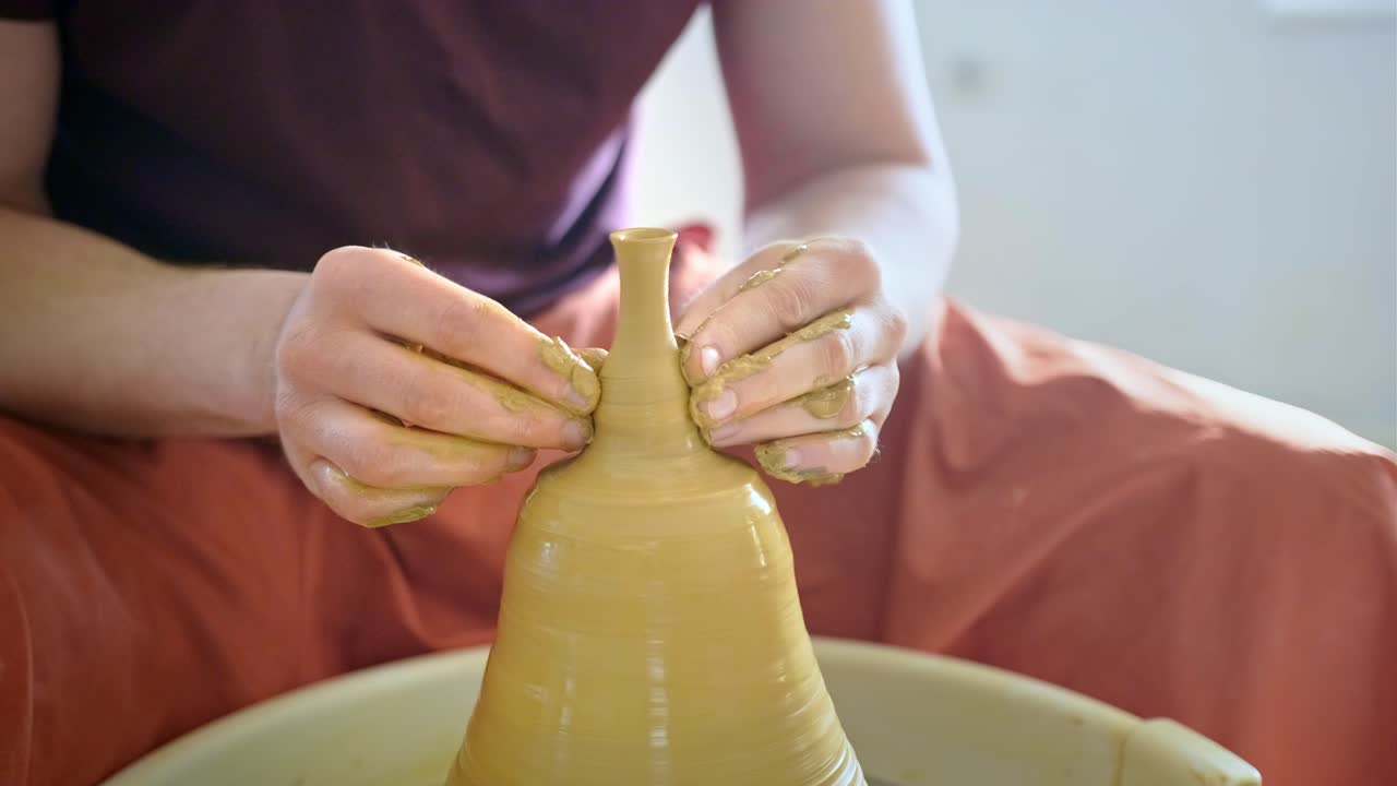 человек, формирующий глину на керамическом колесе