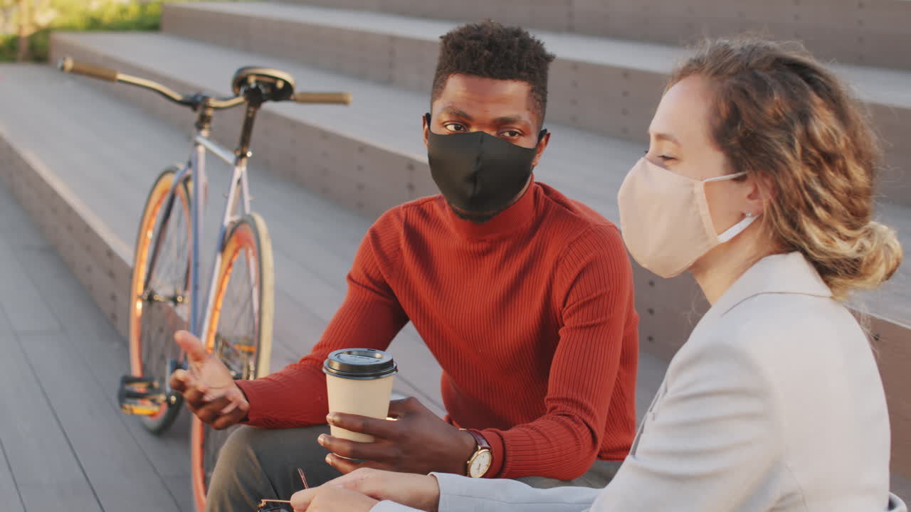 Interracial Business Partners in Face Masks Chatting Outdoors