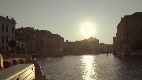 front of a boat cruising towards morning sunrise in canal grande, venice, italy