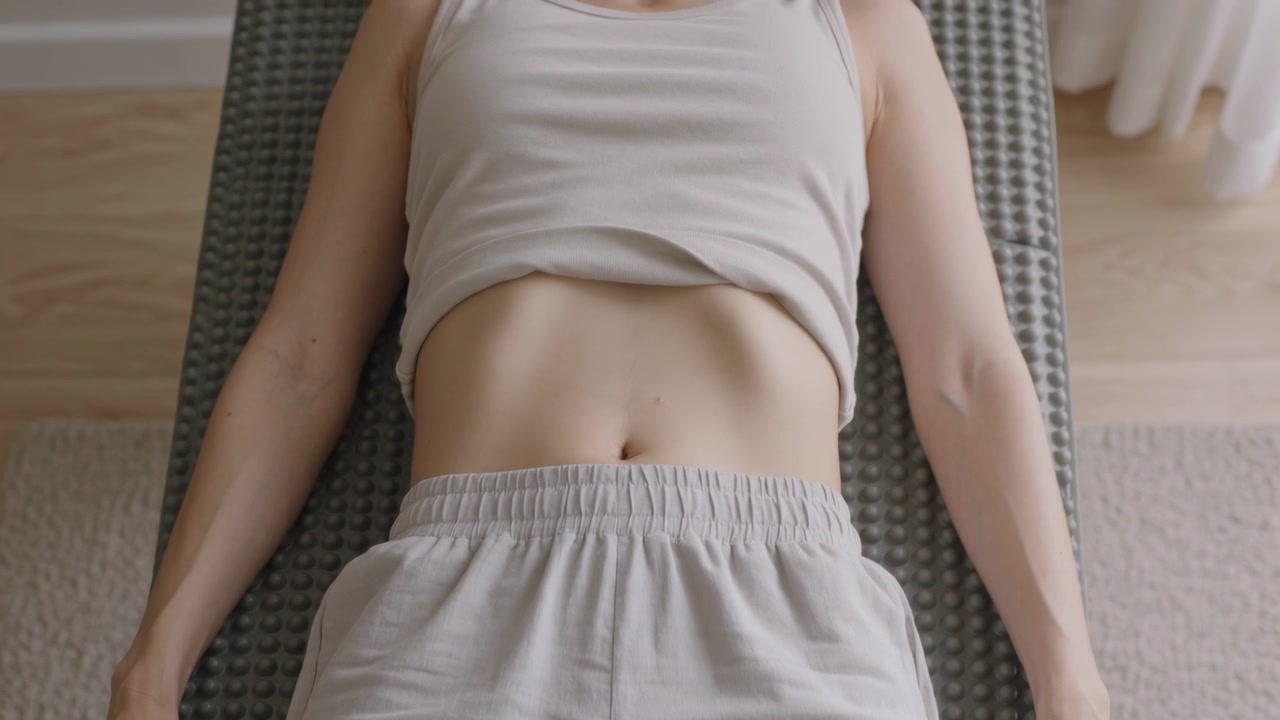 Tight crop revealing woman torso lifting on mat on wood floor, showing tank top and shorts