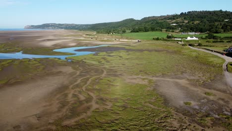 Aerial-view-flying-above-Traeth-Coch-scenic-salt-marsh-moorland-countryside-at-sunset