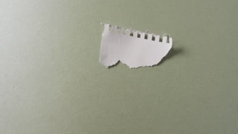 video de primer plano de un pedazo de papel blanco roto sobre un fondo verde