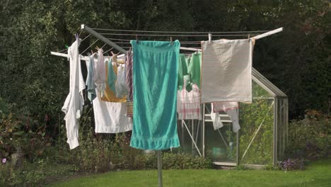 clothes hanging on umbrella clothesline drying rack outside the house