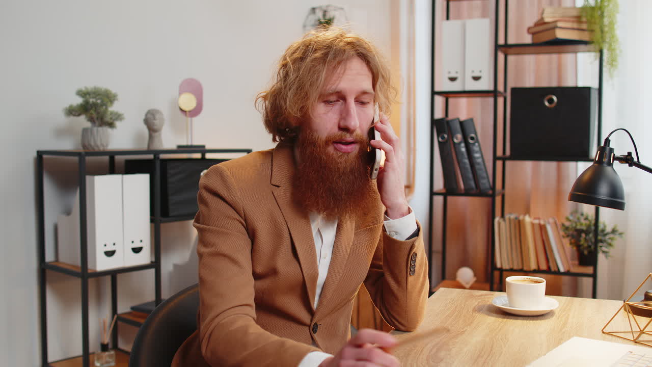 Forretningsmann, freelancer, sitter på kontoret og svarer klienten på mobil smarttelefonsamtale