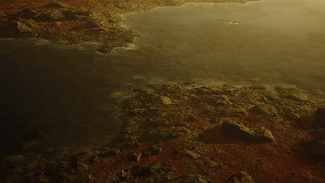 clear river with rocks leads towards mountains lit by sunset