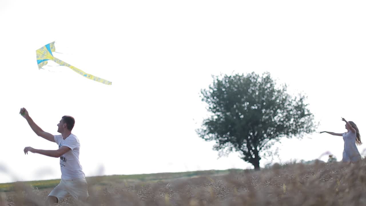 Young Couple Is Enjoying Their Weekend. Young couple is enjoying their weekend outdoor activities and having fun flying a kite