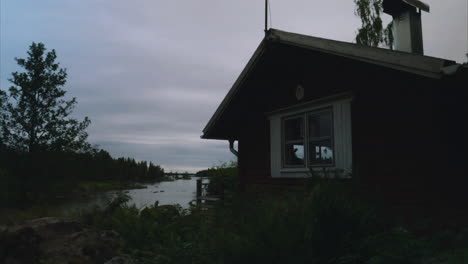 Small-cabin-in-remote-location-by-the-lake-in-Finland,-Time-lapse-tilt-up-shot