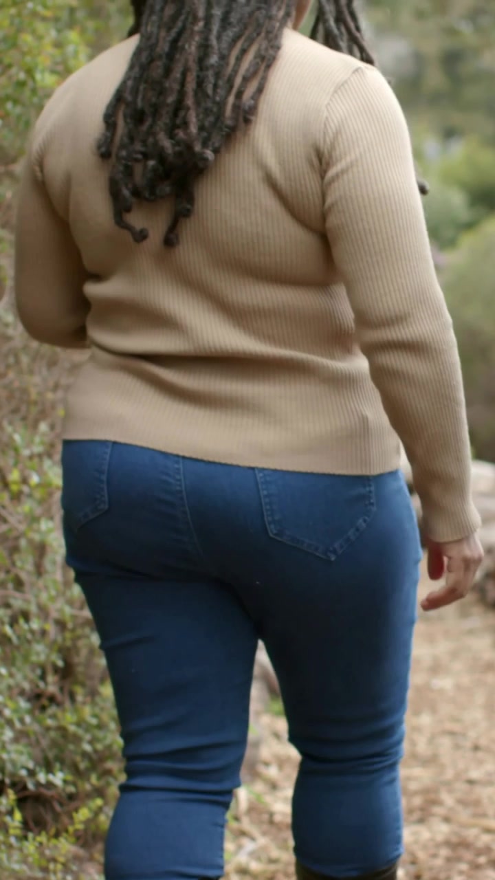 Video verticale: Passi di stivali, donna che cammina con un maglione beige su un sentiero con un compagno vestito di verde
