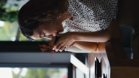 Vertical-Video-Portrait-Of-Young-Businesswoman-With-Coffee-Works-On-Laptop-Sitting-In-Coffee-Shop