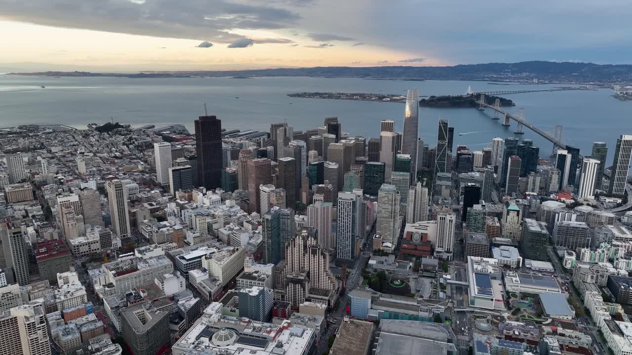 High-angle aerial of downtown San Francisco skyline and Oakland Bay Bridge at dusk