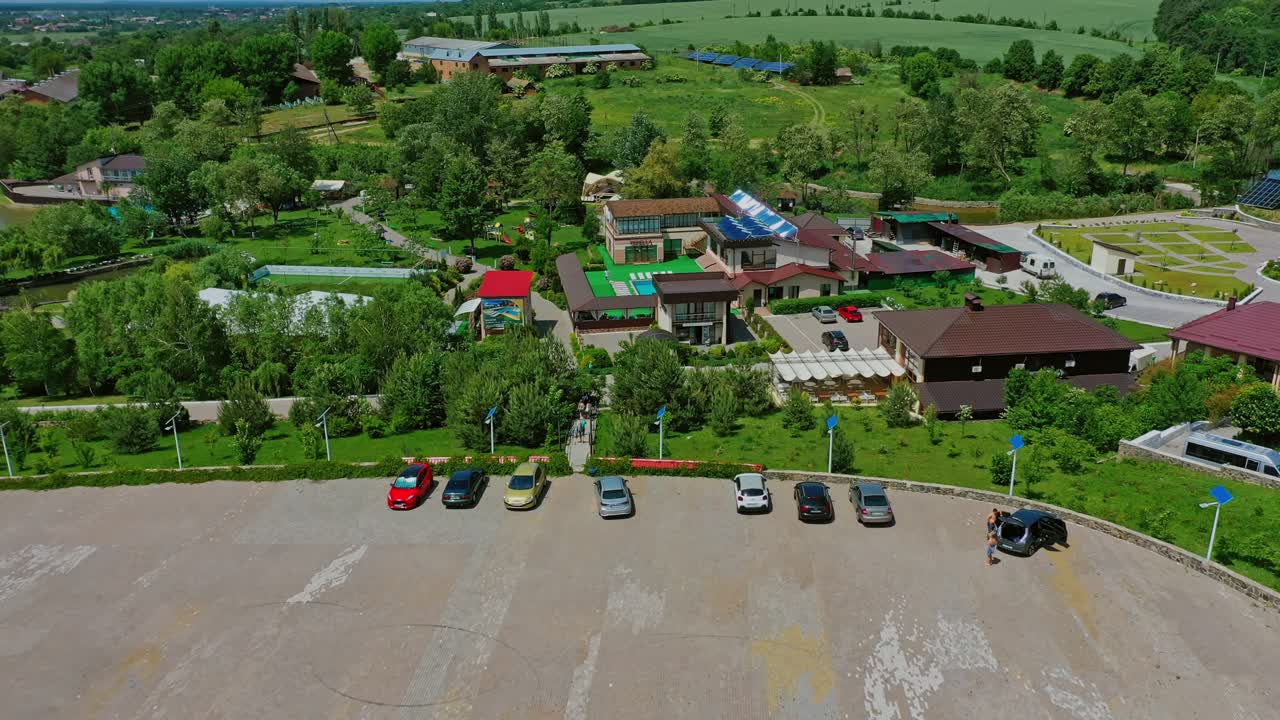 Recreation complex among green nature. Place for car parking near the resting zone. Innovative solar panels on roofs and field in summer. Aerial view.