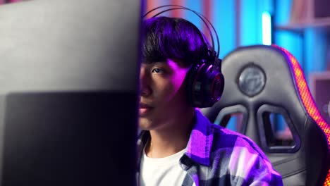 close up of serious asian teen boy gamer playing video game on computer