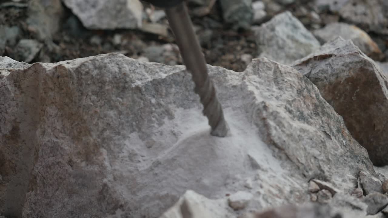 Zooming shot of a driller digging a hole into a rock coming to a stop in slow motion
